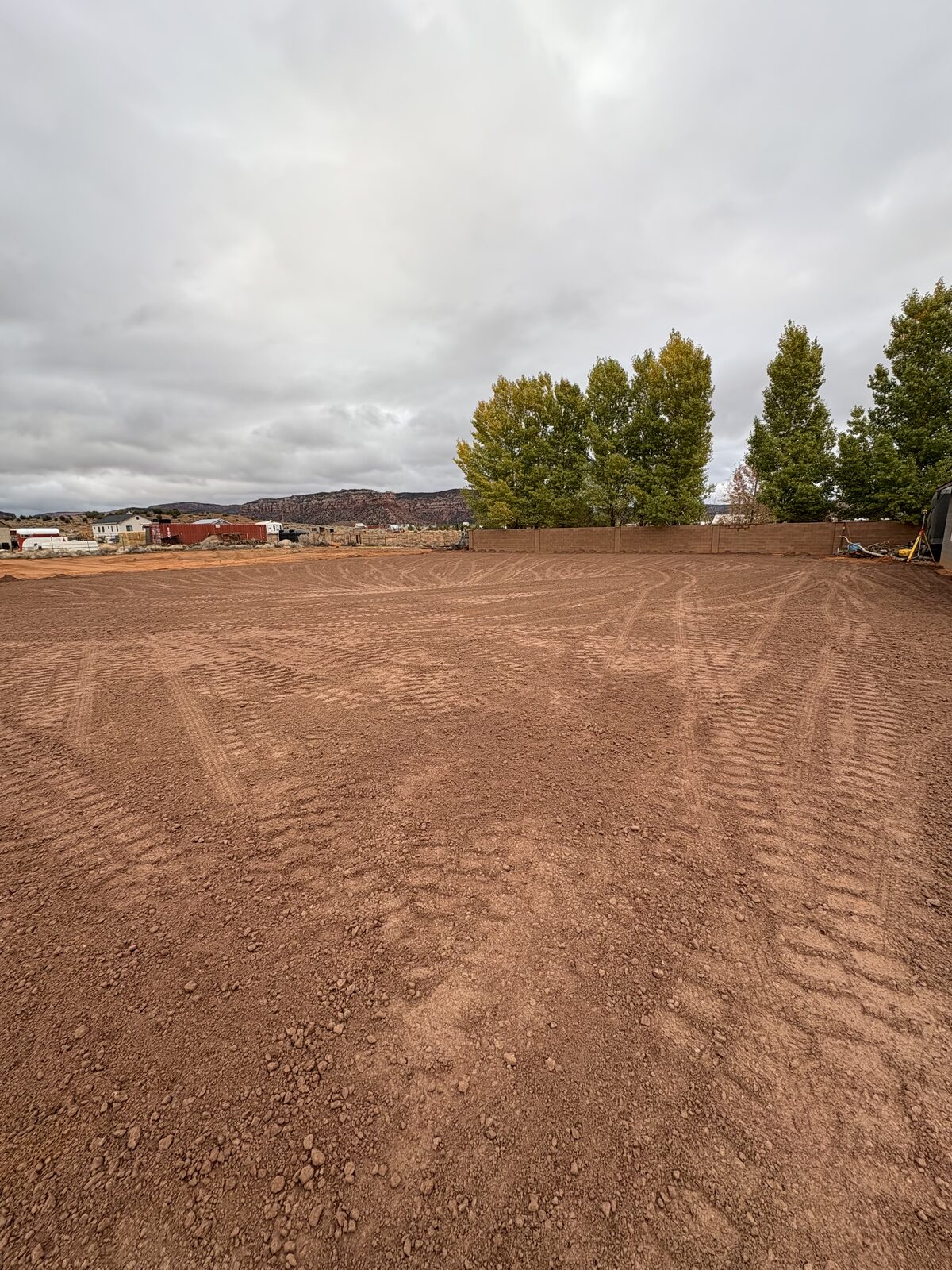 Freshly graded residential building pad with tire tracks across red Southern Utah dirt — Roxor South site grading job in Apple Valley